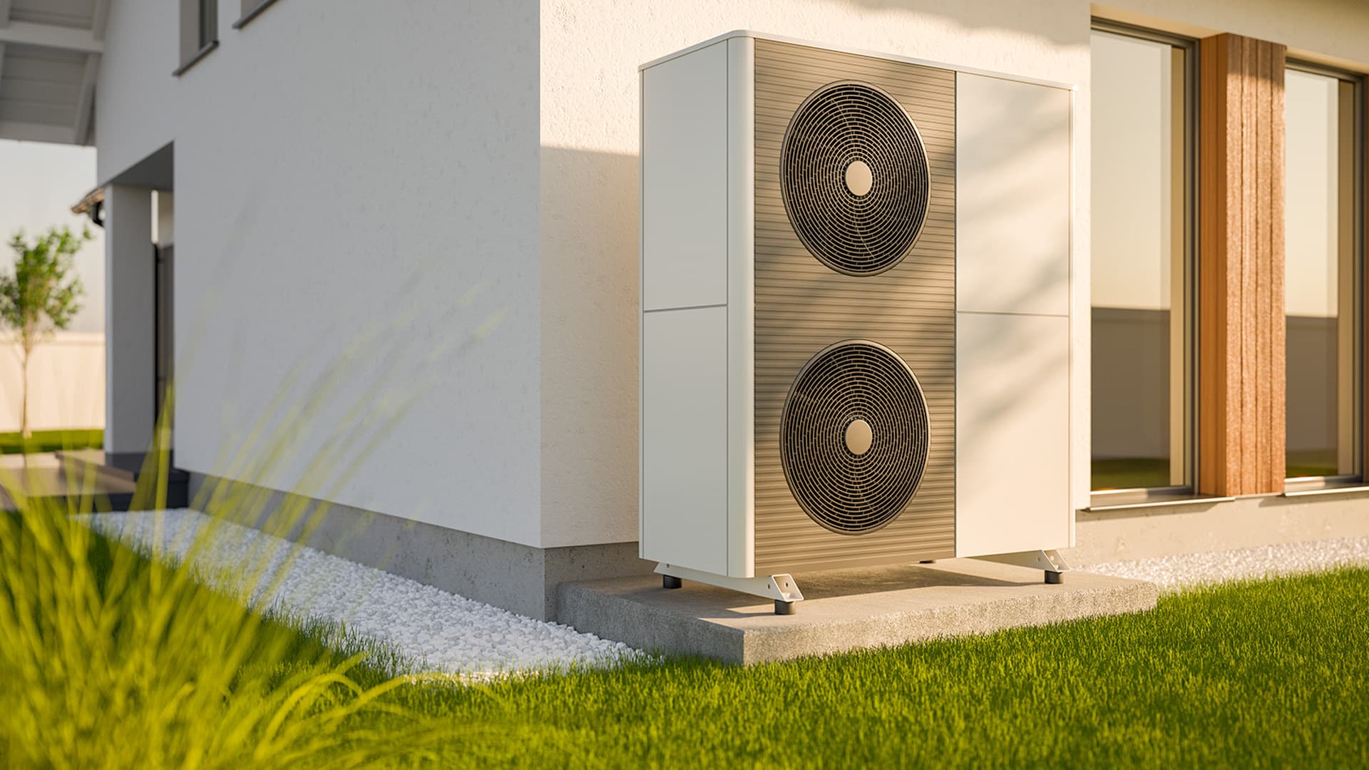 Moderni lämpöpumppu, jossa on kaksoistuuletin, asennettuna valkoisen talon ulkopuolelle, vihreän nurmikon ja sorareunuksen ympäröimänä.