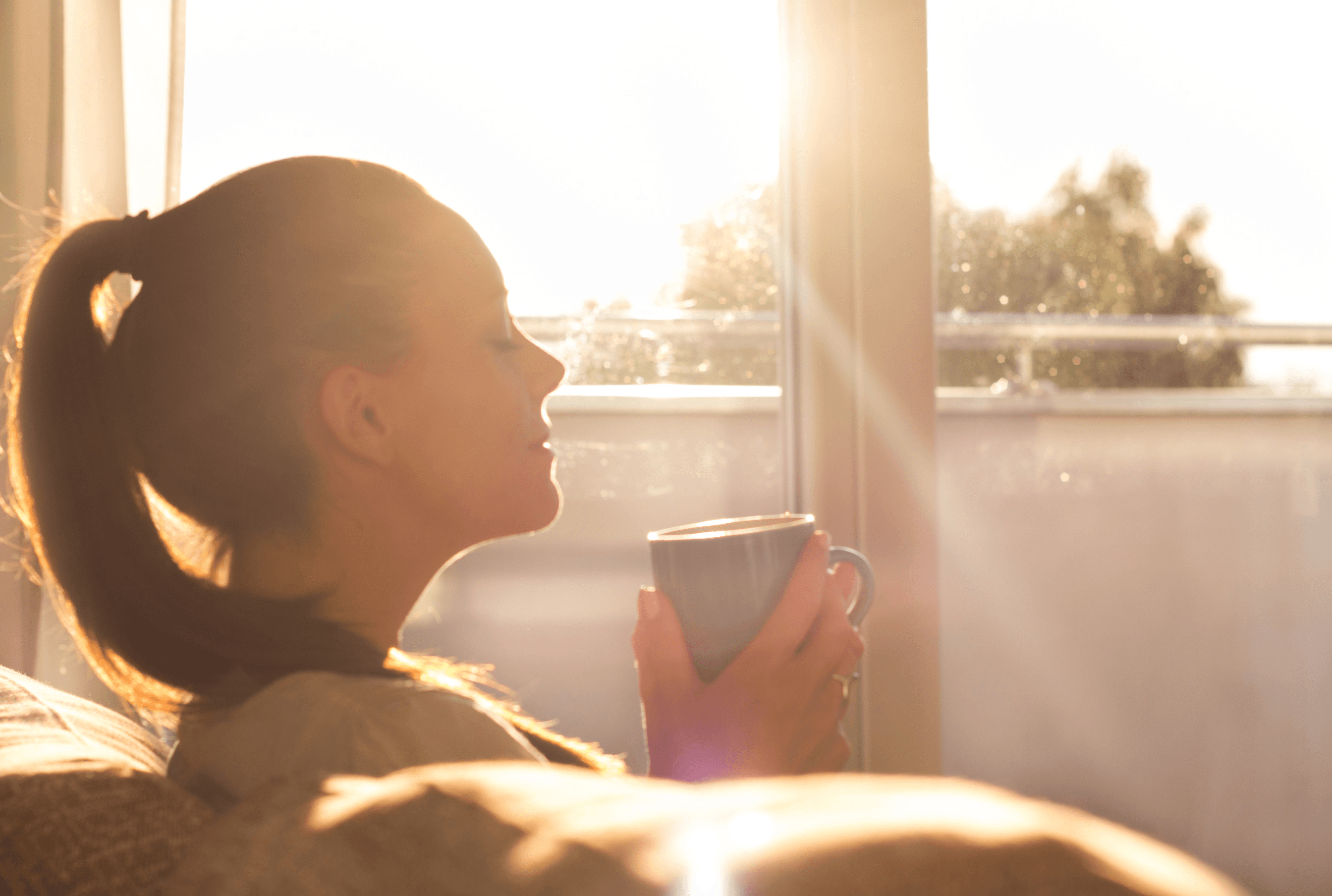 Nainen nauttii kupillisen kahvia auringonpaisteessa